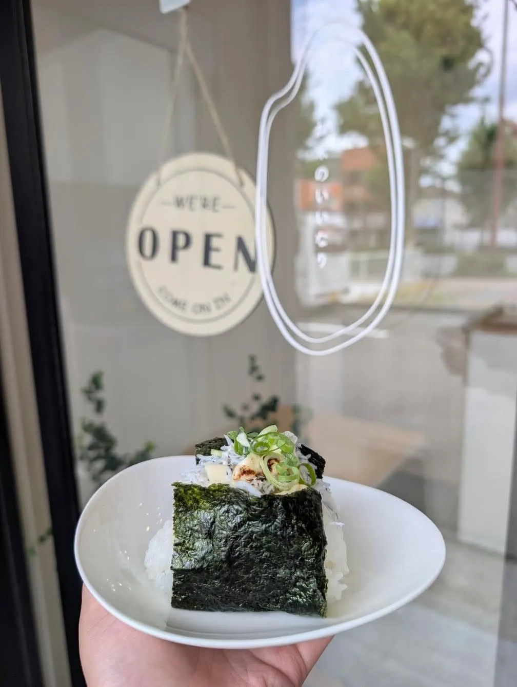 店の入口でおにぎりを手に
